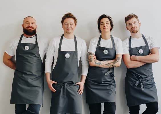 Czworo szefów kuchni prezentuje swoje fartuchy z logo "Chefs for Change" – są liderami roślinnej kuchni.